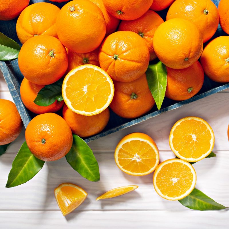 Fresh orange fruits with leaves on wooden table